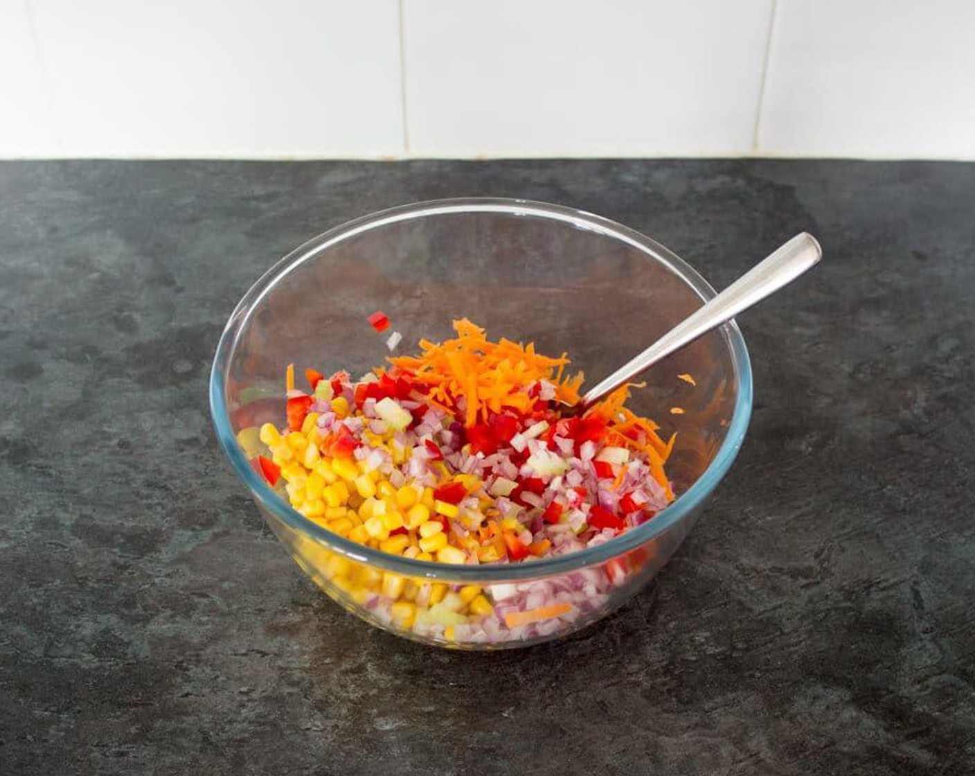 step 2 Meanwhile, if you haven’t already, prepare Red Chili Pepper (1), Sweet Corn (150 g), Carrot (1), Celery (1 stalk), Red Onion (1/2), and Fresh Parsley (1 Tbsp). Then place them all into a large mixing bowl. If you like, save a little of each one to scatter over the top when you serve.