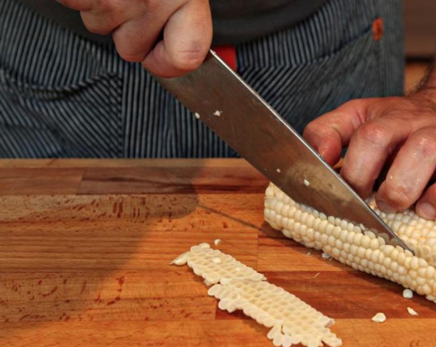 step 3 Using a large, sharp knife and taking care to keep your fingers above and out of the way of the knife, run the bald down the outside edge of the ear to cut kernels away from the cob. Turn the ear slightly and repeat, until all the kernels are cut from the cob.
