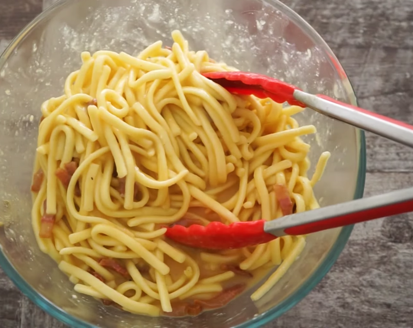 step 9 Now, add the pasta into the egg mixture and combine using a set of tongs. Make sure the egg is smothering every strand of pasta and the guanciale is spread right through.