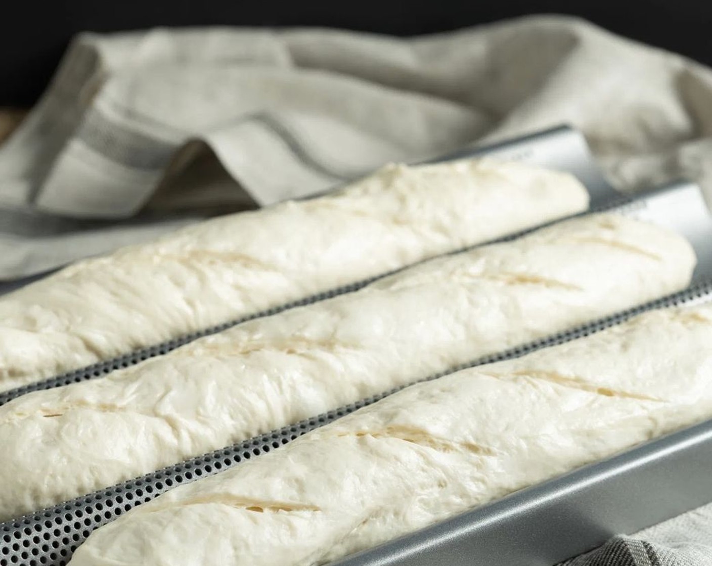 step 13 Using a sharp knife or bread lame, make at least four 4-inch slashes across each loaf. If using parchment paper, remove towels and pull parchment by the corners to flatten.