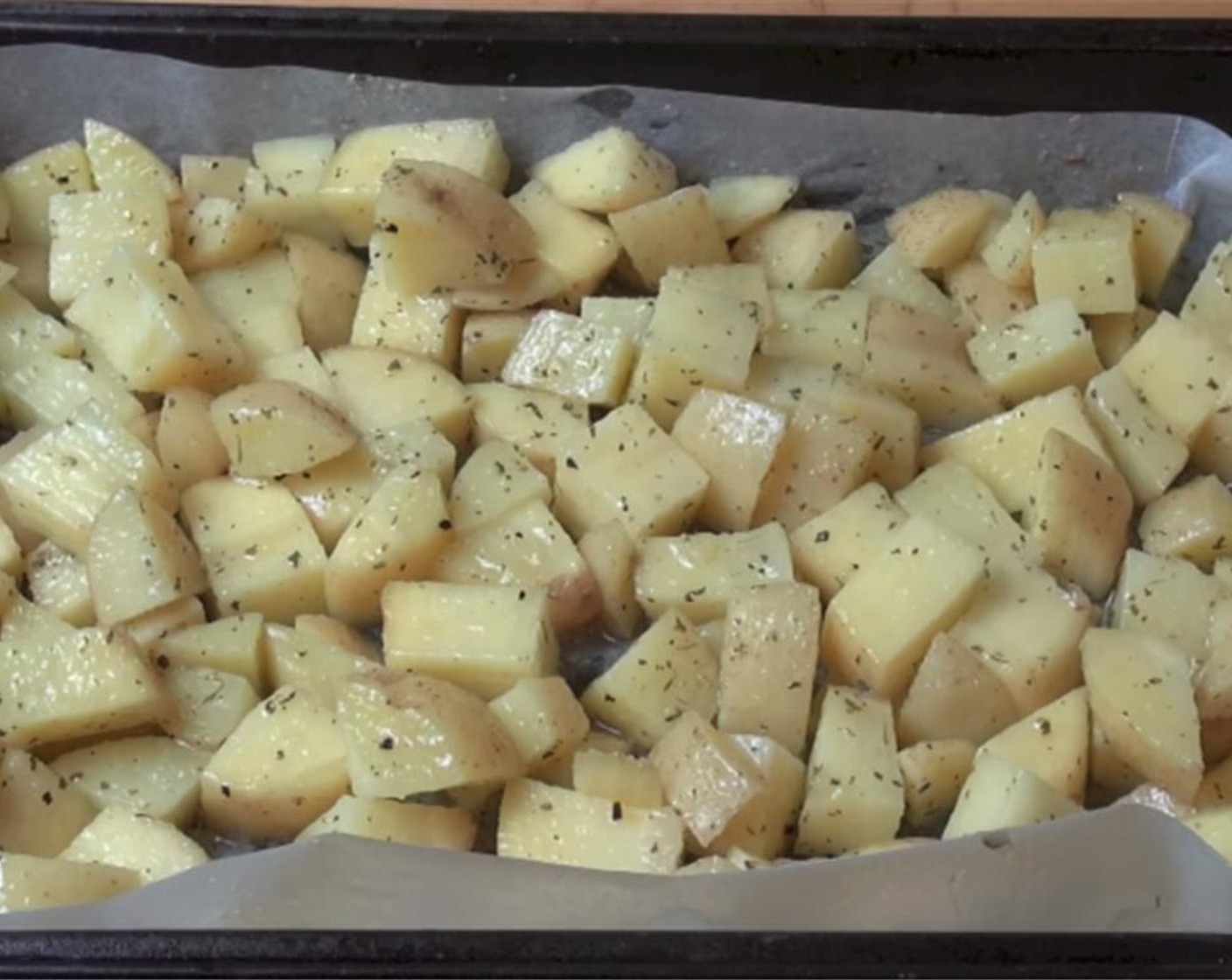step 4 In a roasting pan, line with non-stick baking paper and put the partially cooked potatoes on the pan. Drizzle the mixed seasoning over them and mix well with a wooden spoon.