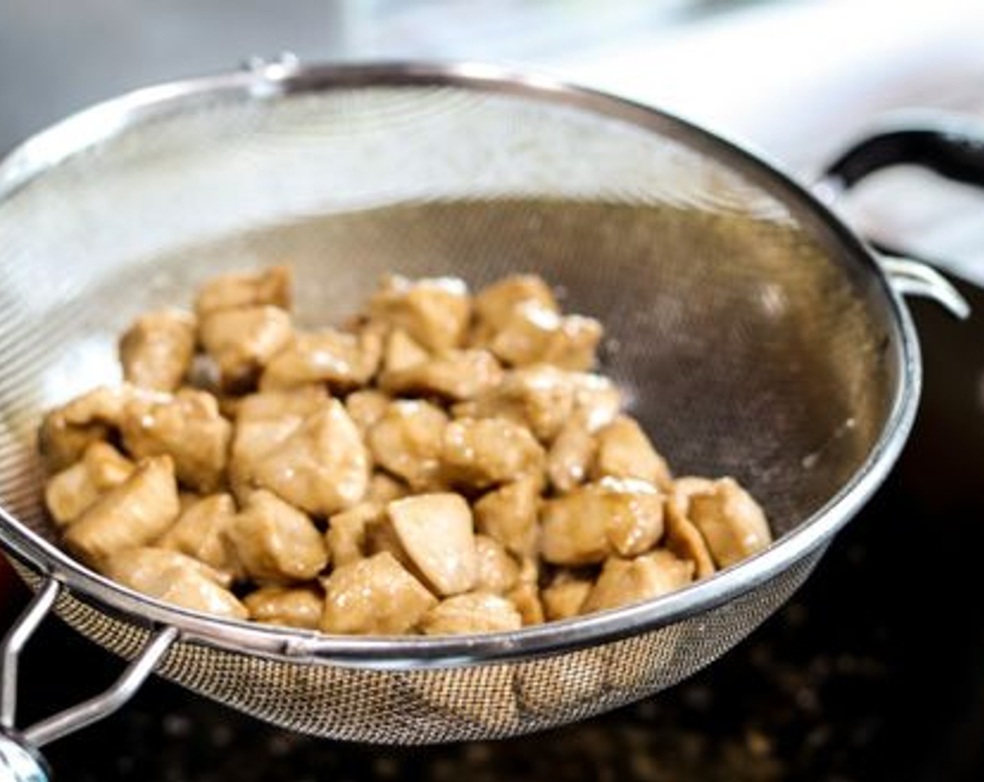 step 7 Once they are about 3/4 of the way cooked, remove the chicken pieces to the fine mesh strainer and hold above the wok to let the oil drain. You can gently shake the strainer to speed up the draining process, but be careful not to shake with too violently as that’ll cause some of the cornstarch to come off and make the chicken a bit mushy. Remove the chicken into another clean large bowl and set aside. Discard the oil in the wok and wipe with paper towels. Set back on stove.