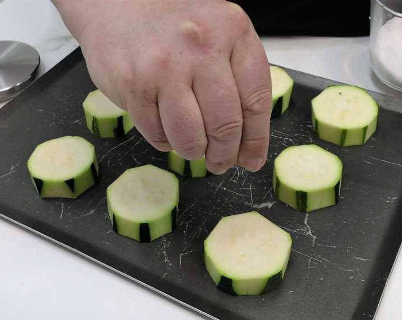 step 1 Clean and slice the Zucchini (1) in 2 centimeter rounds. Peel most of the skin and place them on a baking tray. Sprinkle each round with a bit of salt.