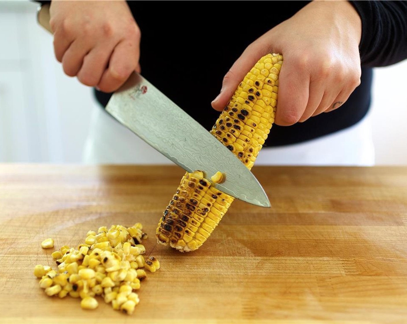 step 10 Place the corn cut side down, on the cutting board, holding it near the top of the ear. Using a sharp knife, start at the top and cut downward with a gentle sawing motion, cutting corn off the cob. Continue cutting until all of the corn is removed.