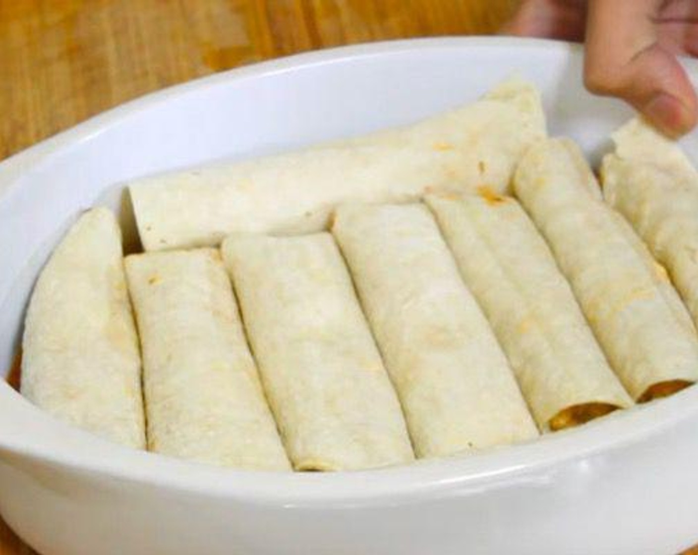 step 5 Heat up the White Corn Tortillas (12) in the microwave or over the stove for about 15 seconds. Place one tortilla on your work surface, add some of the chicken mixture, and roll it up. Place it in your baking pan and repeat the process until you finish with all of the chicken mixture.