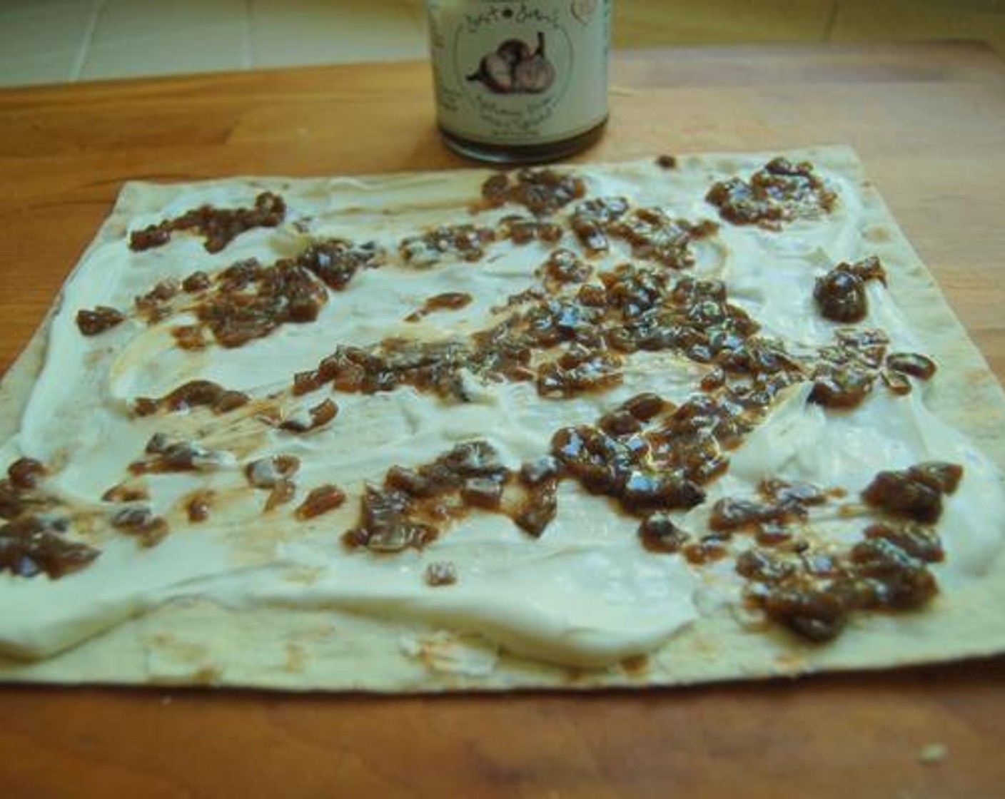 step 2 Spread Crème Fraîche (3 Tbsp) on Flatbread (1) or tortilla, then spoon Just Jan’s® Balsamic Onion Savory Spread (3 Tbsp) over top.