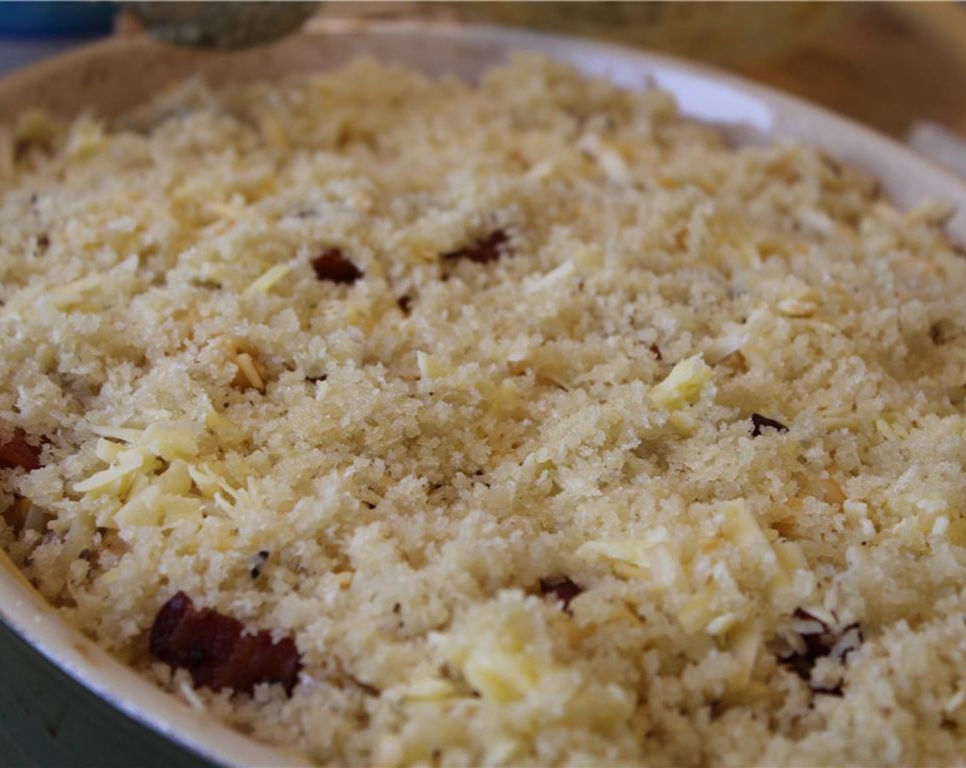 step 18 Sprinkle the remaining bacon over the dish, followed by the cheeses and then the breadcrumbs.