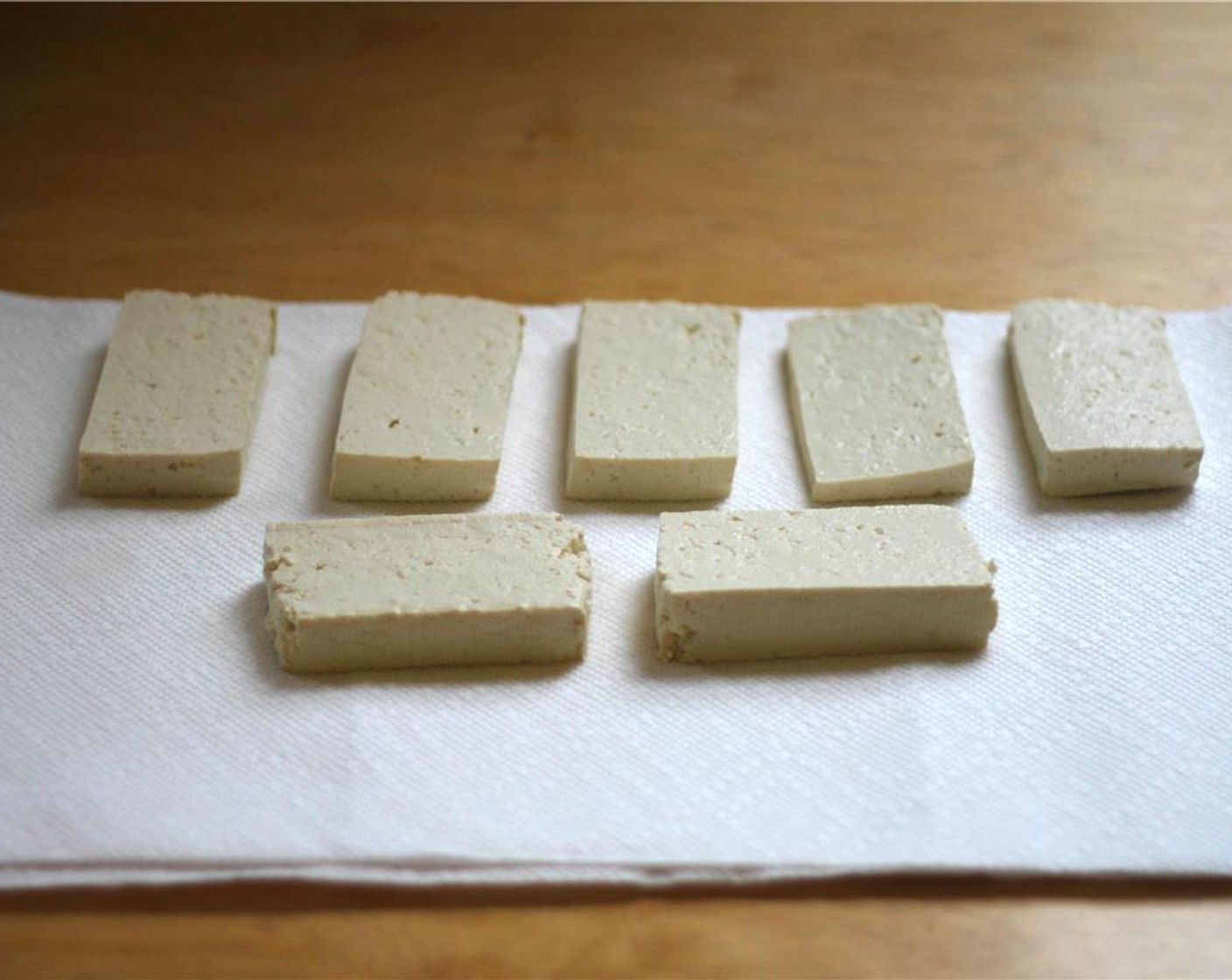 step 6 Slice Extra Firm Tofu (1 pckg) into six or slabs and arrange on top of three layers of paper towel. Cover with paper towels and press gently to absorb as much of the water as possible. Allow to sit and further dry out while proceeding.
