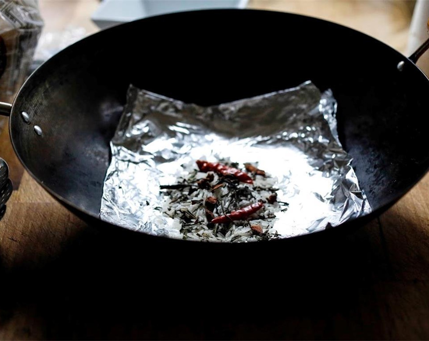 step 9 In a small bowl, mix the White Rice (3 Tbsp), Green Tea Leaves (2 Tbsp), Granulated Sugar (2 Tbsp), Star Anise (2), and Dried Chili Peppers (2). Place the smoking ingredients in the wok, spreading it out, to about 4 inches in diameter.