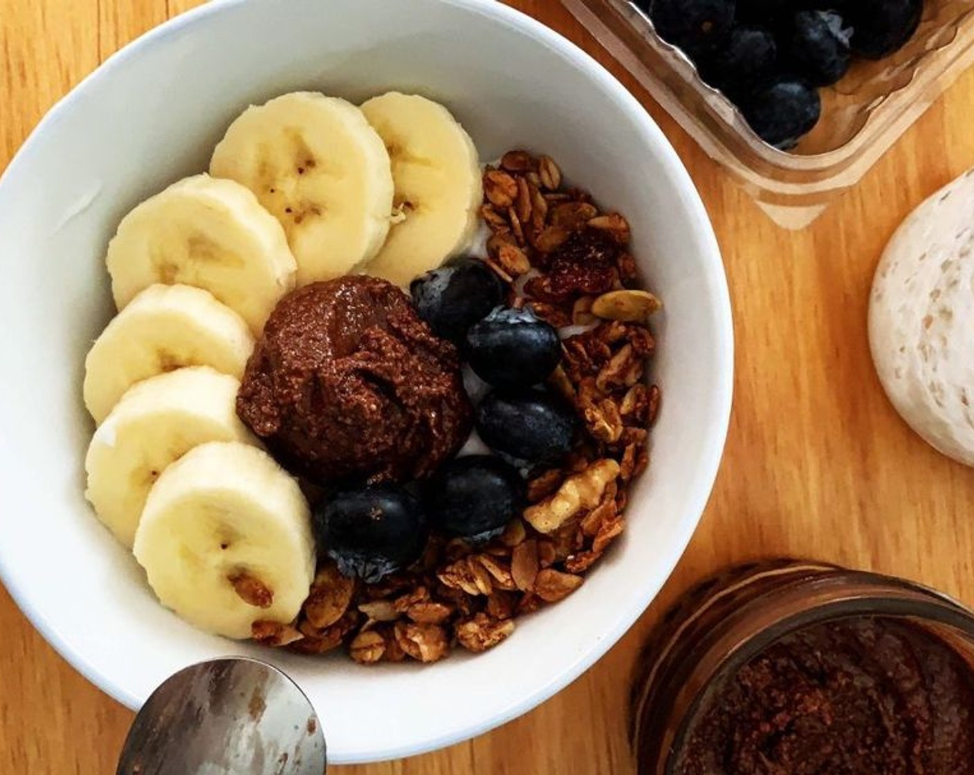 step 1 Take a large bowl and add in Unsweetened Coconut Yogurt (to taste), then top it off with some Granola (to taste), Bananas (to taste), Fresh Blueberries (to taste) and a spoon of Chocolate Almond Butter (1 Tbsp).