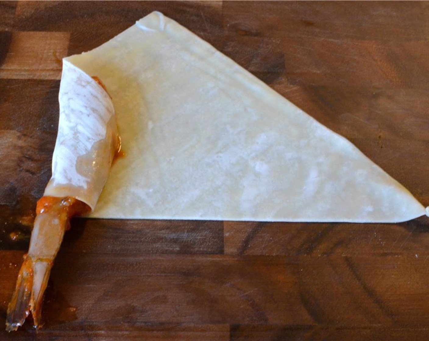 step 9 Place a shrimp on the left side of the wrapper with the tail sticking out and fold over the left corner, wrapping the shrimp as tightly as you can.