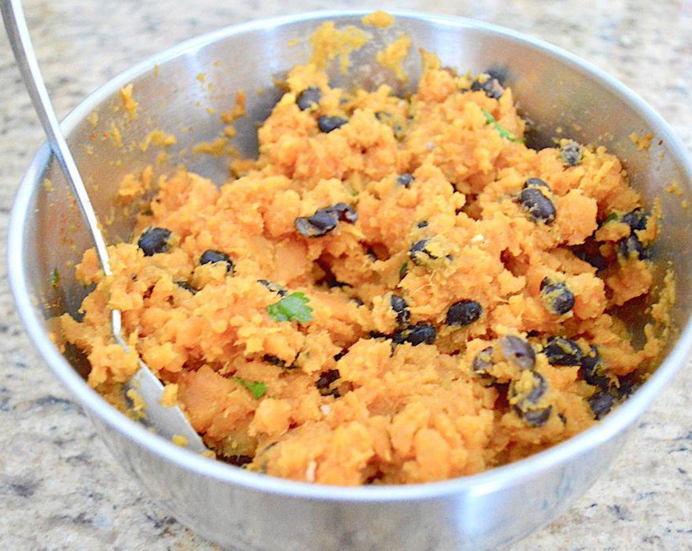 step 3 When they are cool enough to handle, cut them in half and scoop the flesh right out of the skin into a mixing bowl. Then mash them well with a fork. Stir in the Canned Black Beans (1 cup), Fresh Cilantro (1 Tbsp), Dried Onions (1/2 tsp), McCormick® Garlic Powder (1/2 tsp), Paprika (1/2 tsp) and Ground Cumin (1/2 tsp).