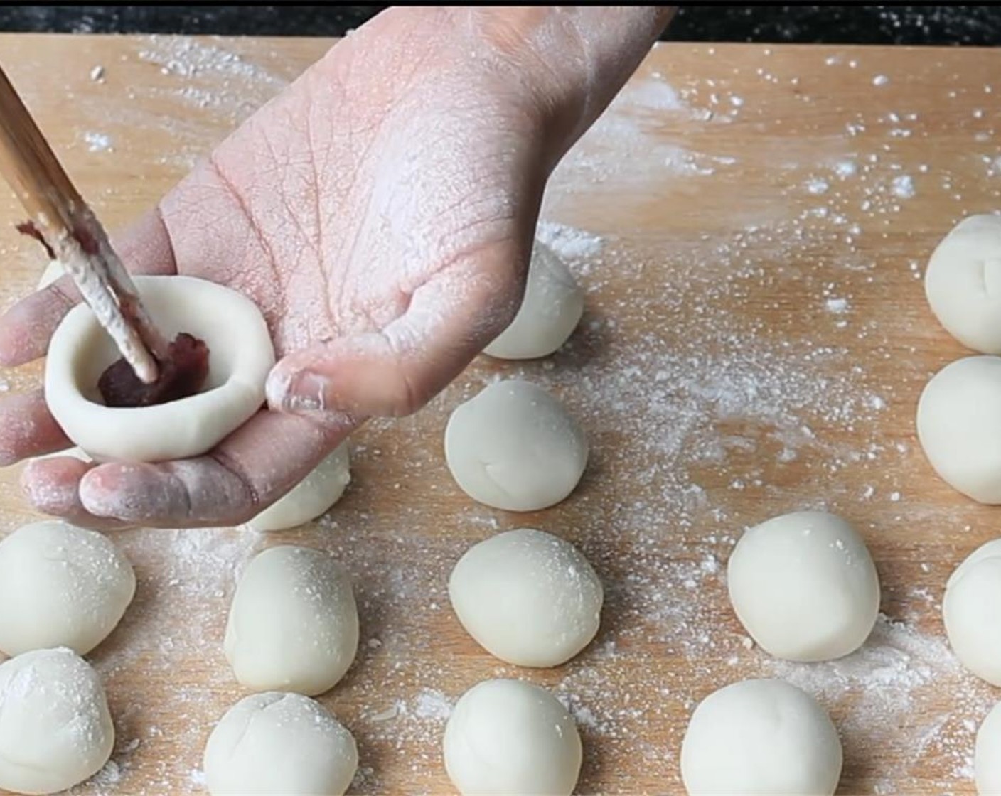 step 4 Further shape the dough into long log and then divide into 20 equal portions. Shape each portion into a round ball. Then, shape each round ball into bowls, and wrap around 1 teaspoon of the Red Bean Paste (3 Tbsp) in. Seal completely and shape into balls again.