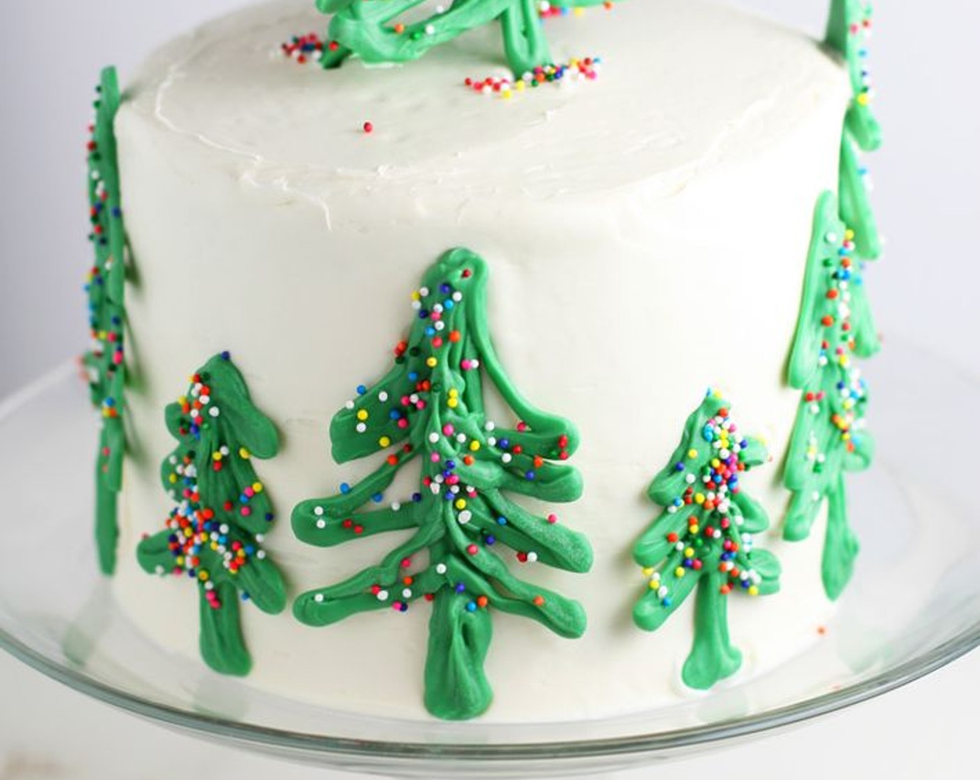 step 8 Continue frosting the entire cake. Smooth the sides with an offset icing spatula. Gently add chilled candy Christmas trees to the side of cake and on top, if desired. Serve immediately or store in refrigerator for up to 5 days.