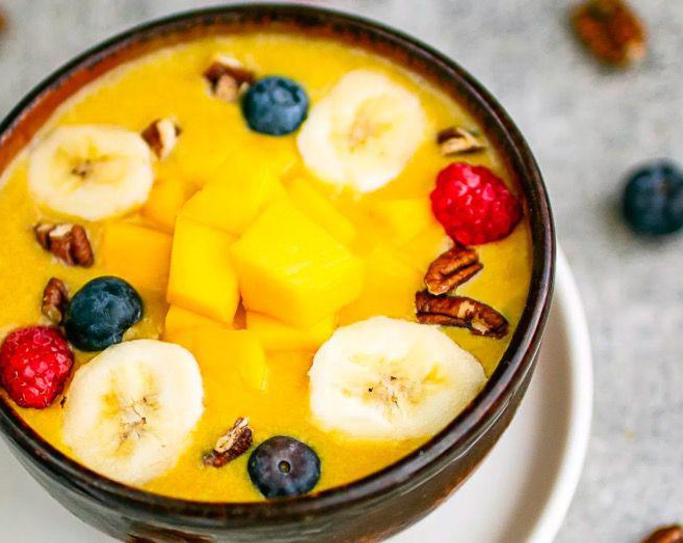 step 2 Pour into two serving bowls and top with Frozen Blueberries (1 handful), Pecans (1/3 cup), remaining Mango (1 cup) and Banana (1/2).