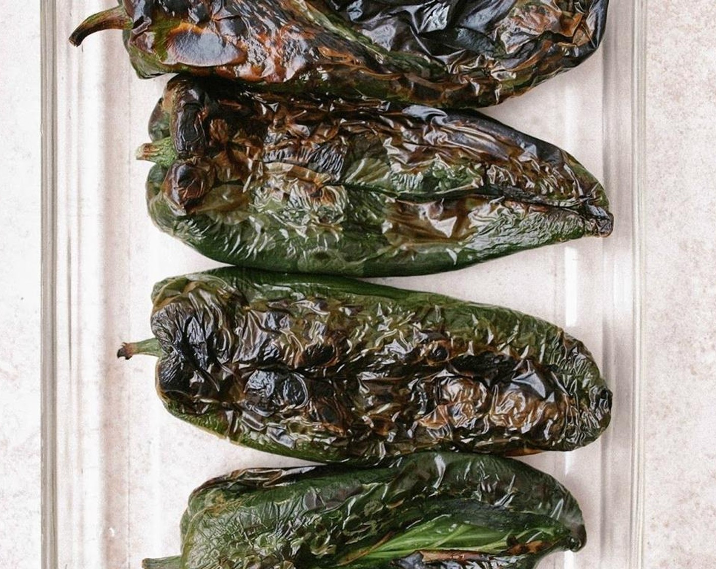 step 9 Remove the peppers from the oven. Let cool a few minutes in the dish covered with saran wrap. Remove any loose skin off the pepper. Gently slice each pepper, making a slit down the center of one side, without cutting into the other side.