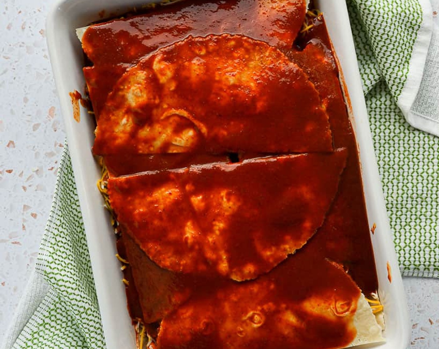 step 10 Make a second layer of tortillas using the six remaining halves. Lay four with the flat edge touching the baking dish side and the final two halves in the center. Layer again with the remaining Enchilada Sauce (3/4 cup).