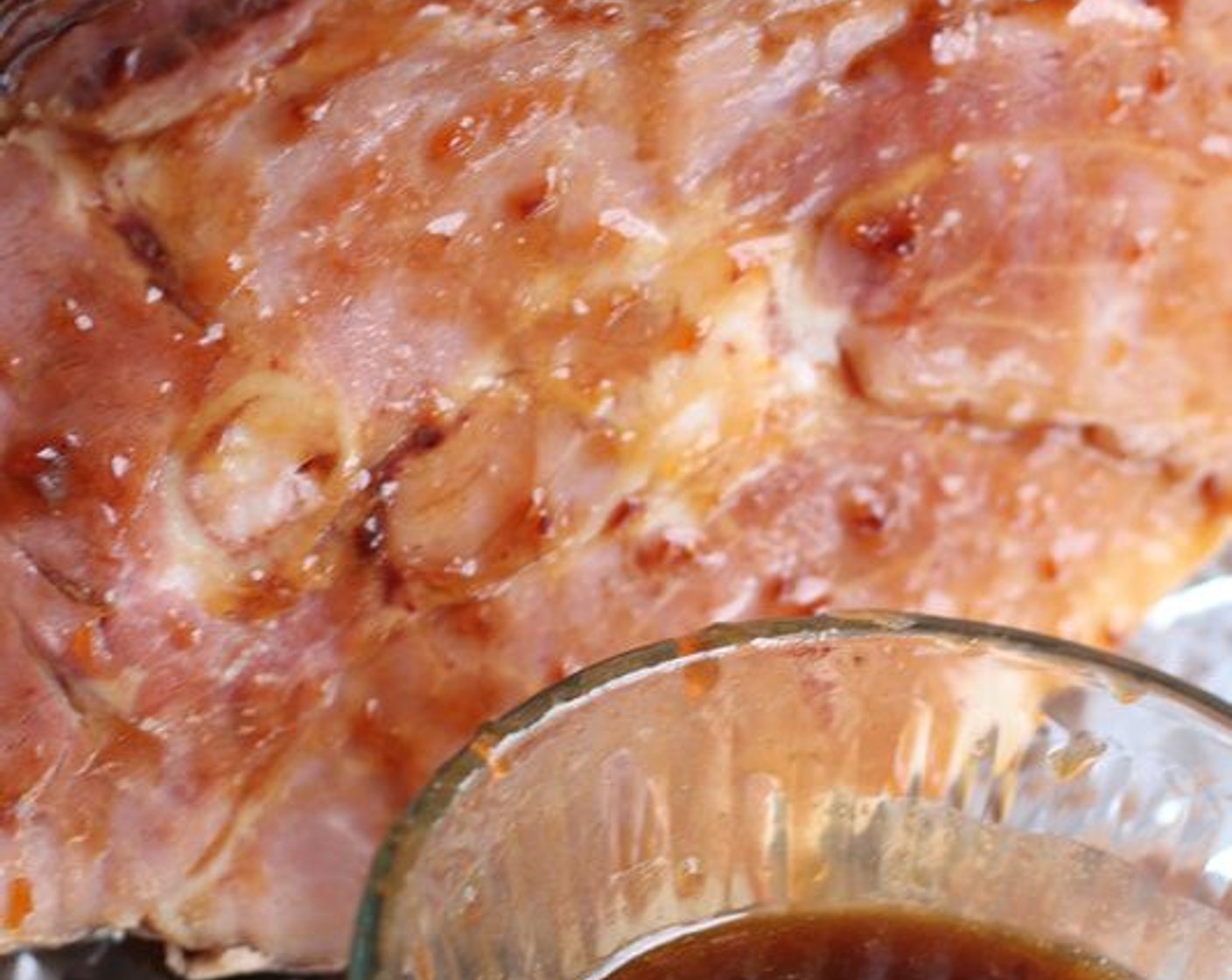 step 7 Remove ham from oven; carefully unwrap ham and discard foil. Spoon juices from the bottom of the roasting pan over the top of the ham. Brush the top and between slices of the ham with half of the remaining glaze.