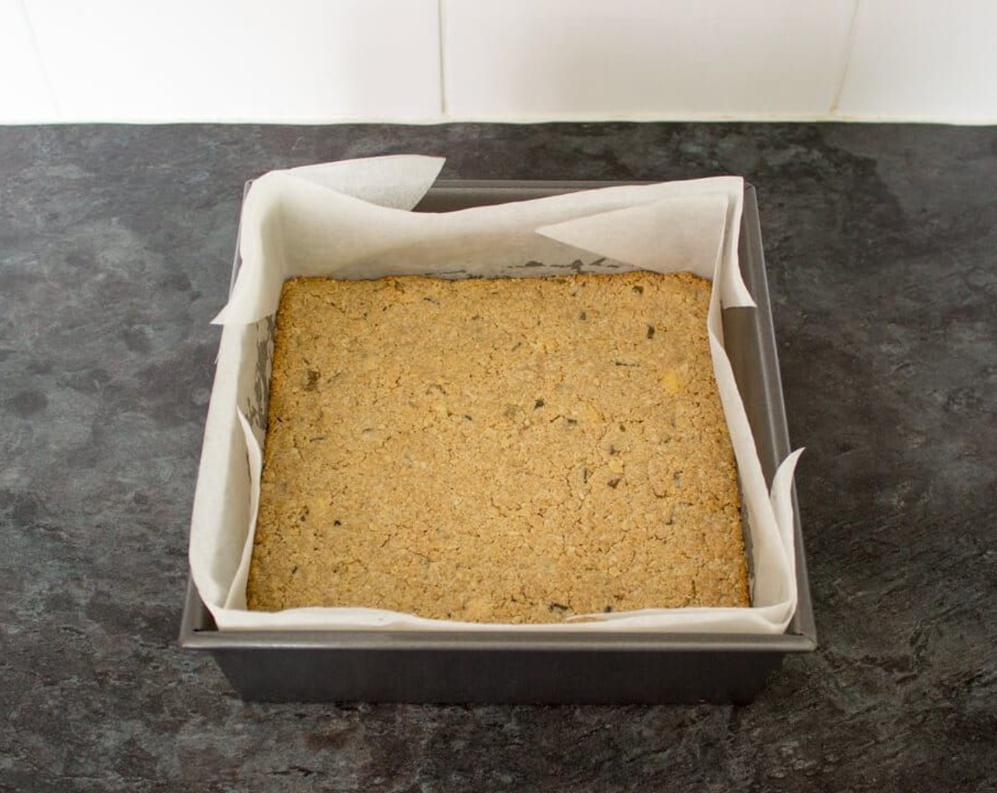 step 7 Tip it all into the prepared tin and press very firmly with the back of a metal spoon. Bake in the preheated oven for 15-20 minutes until the edges have started to turn golden.