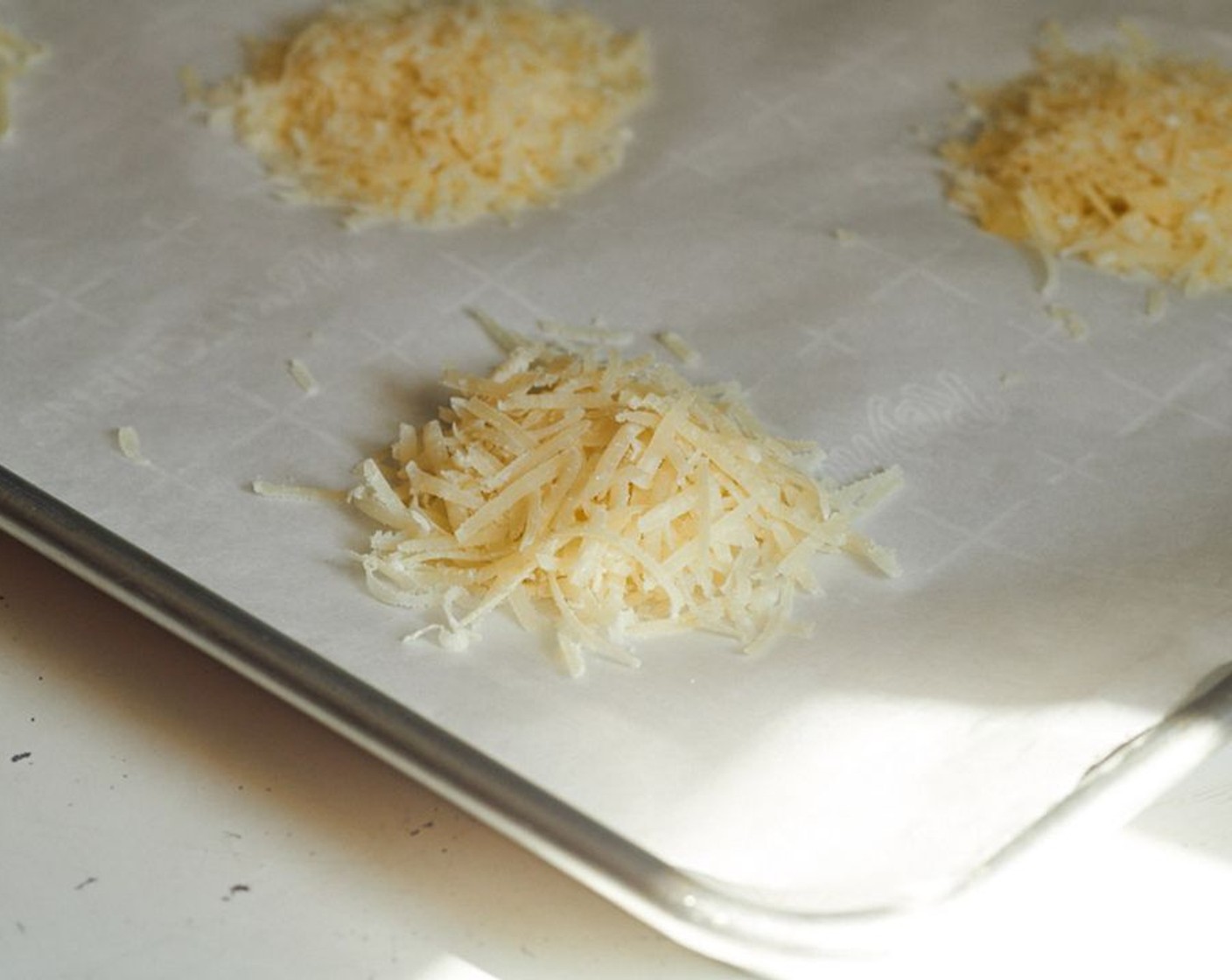 step 3 Heap two tablespoons of grated cheese for each crisp into well-spaced piles on the parchment. You can gently tap it down on top if you want.