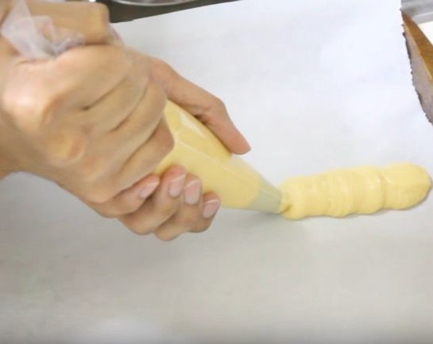 step 7 On a baking pan lined with parchment paper, squeeze dough out into 3 to 4-inch lines. Brush each gently with water.