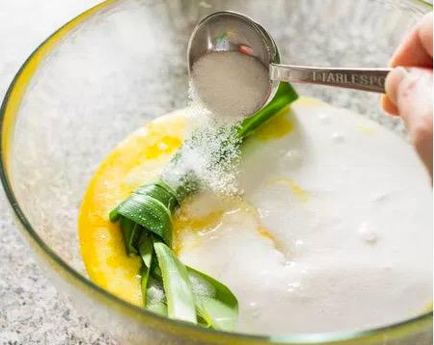 step 2 Add Coconut Milk (1 cup), Pandan Leaves (1) (tied into a knot), 2 tablespoons of Granulated Sugar (1/3 cup) and a pinch of Salt (1 pinch) to the egg yolks. (Set the additional 3 tablespoons of sugar aside)