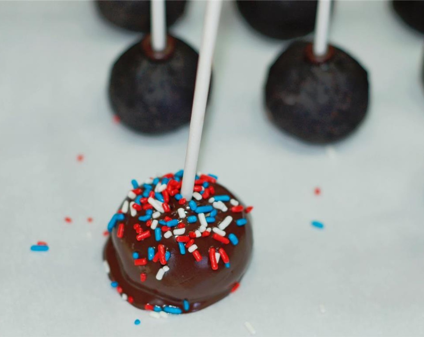step 7 Then place pops on wax paper, stick facing upwards. Add some of the Red, White, and Blue Sprinkles (1/2 cup) before the candy melt hardens. Repeat with remaining truffles.