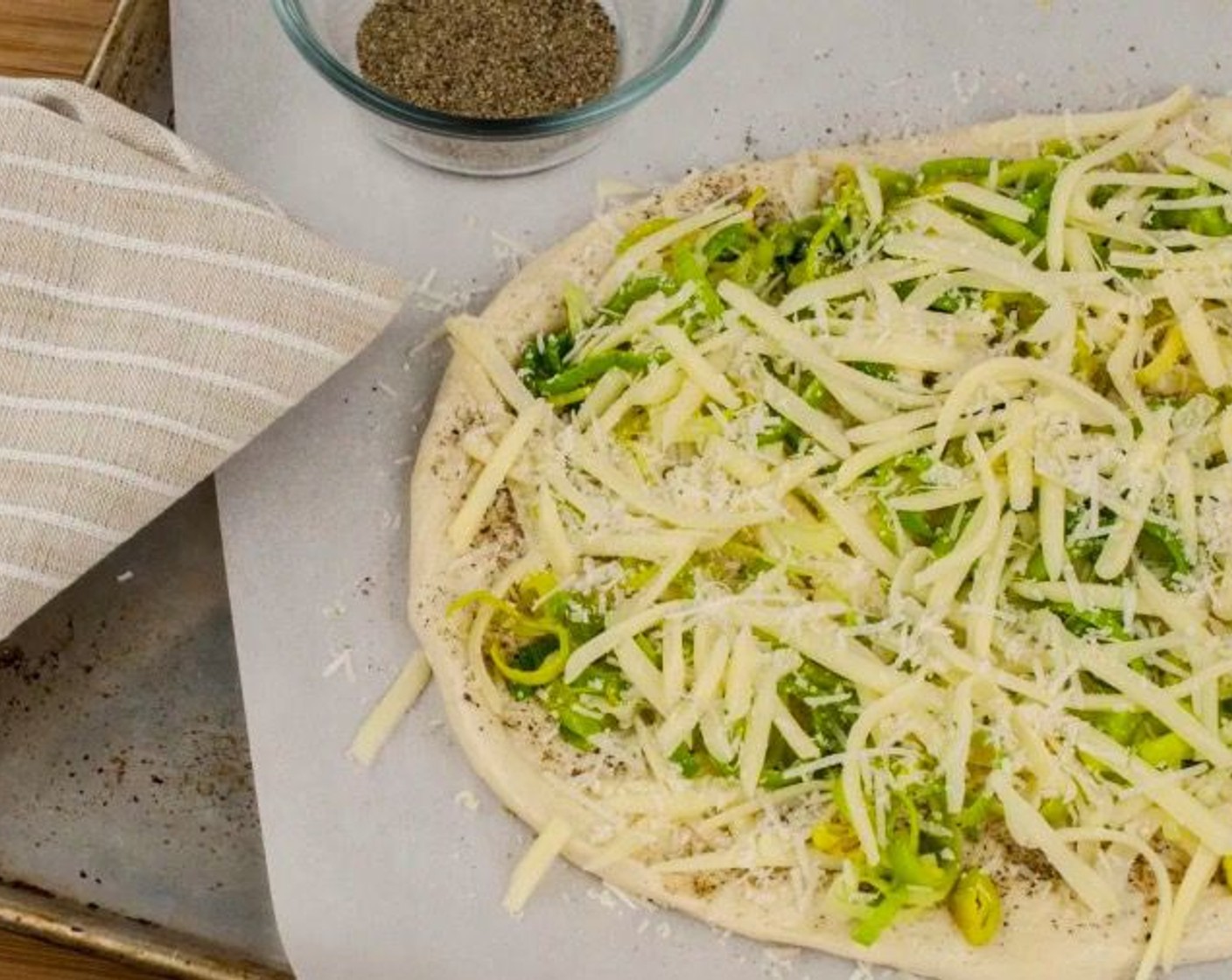 step 10 Sprinkle a quarter of the Shredded Mozzarella Cheese (1 1/2 cups) evenly over each dough round and top each with half of the sautéed leeks. Add another quarter of mozzarella cheese and half of the Parmesan Cheese (4 Tbsp) to each dough round. Season both rounds with additional salt.