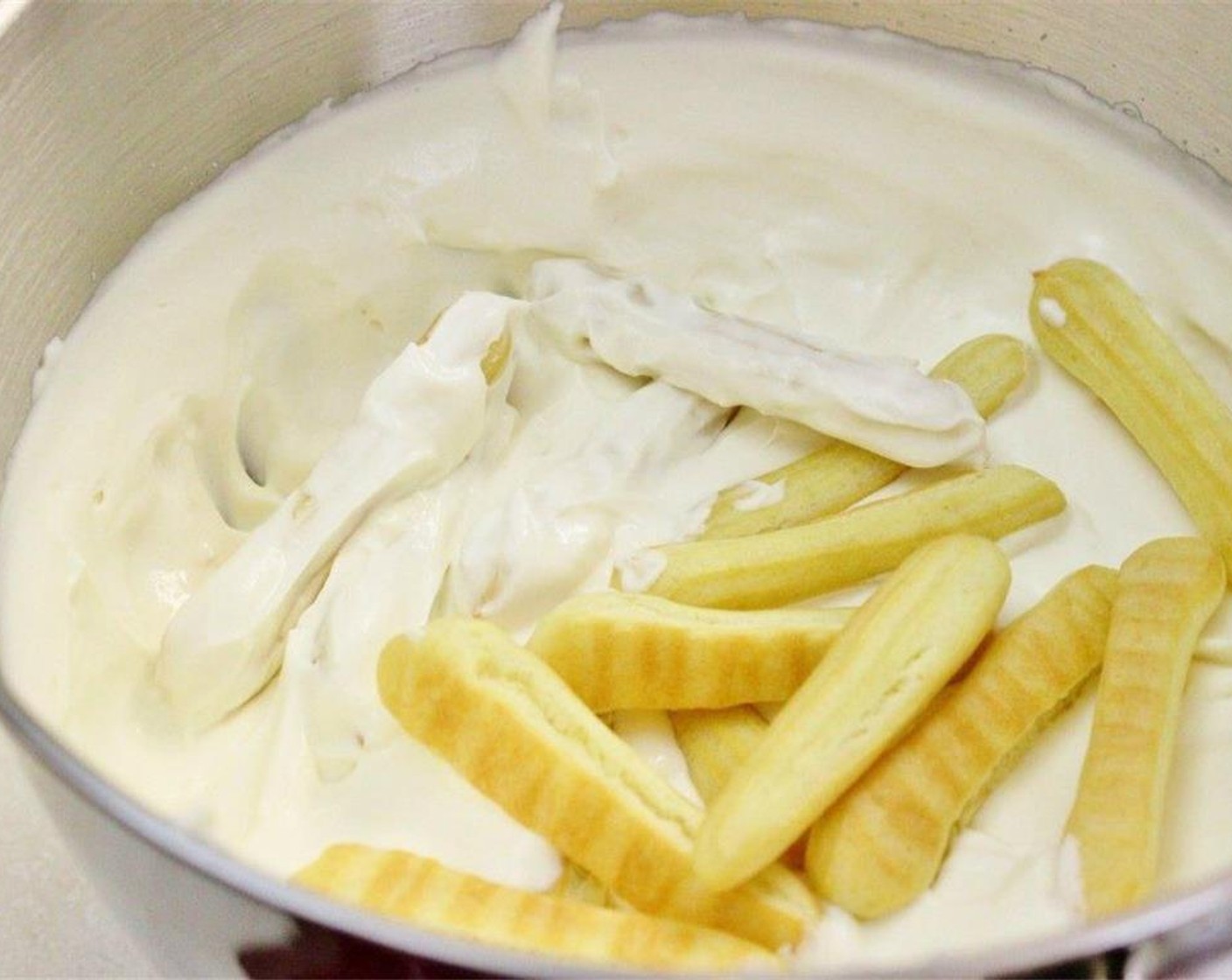 step 8 In a 9 inch spring form pan, spread some frosting, about 1/4 cup, on the bottom of the pan. Dip the lady fingers in the frosting bowl.