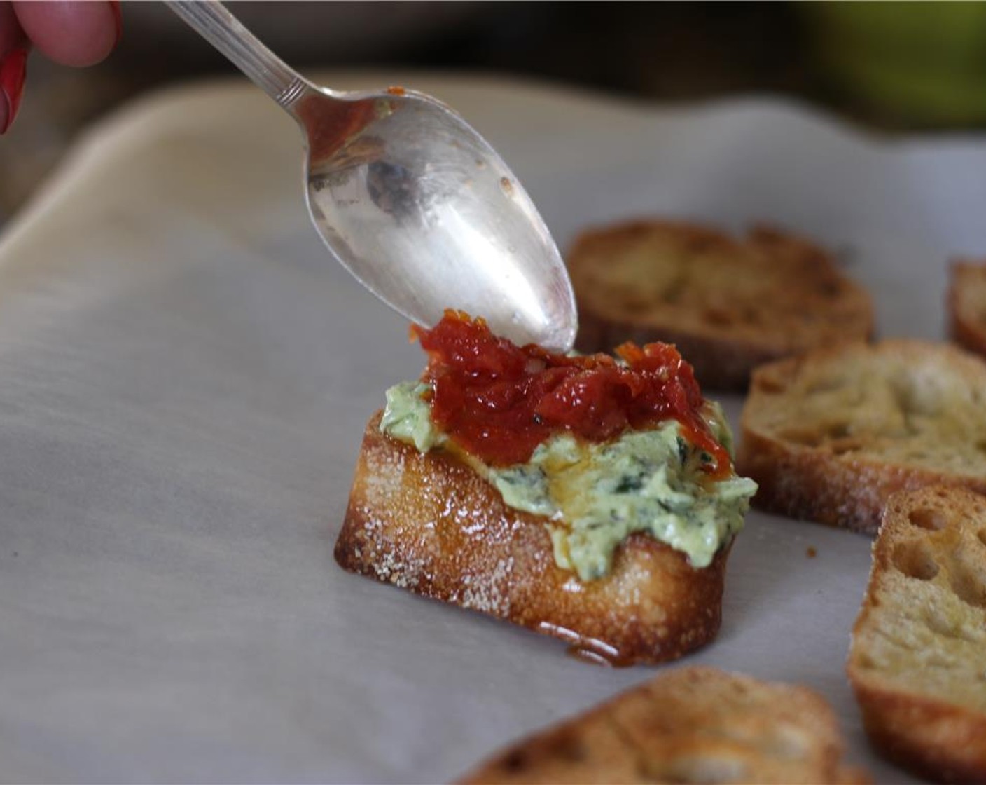 step 8 To assemble the crostini, spread a layer of creamy pesto, followed by a dollop of roasted tomatoes. Drizzle with balsamic glaze and serve immediately.