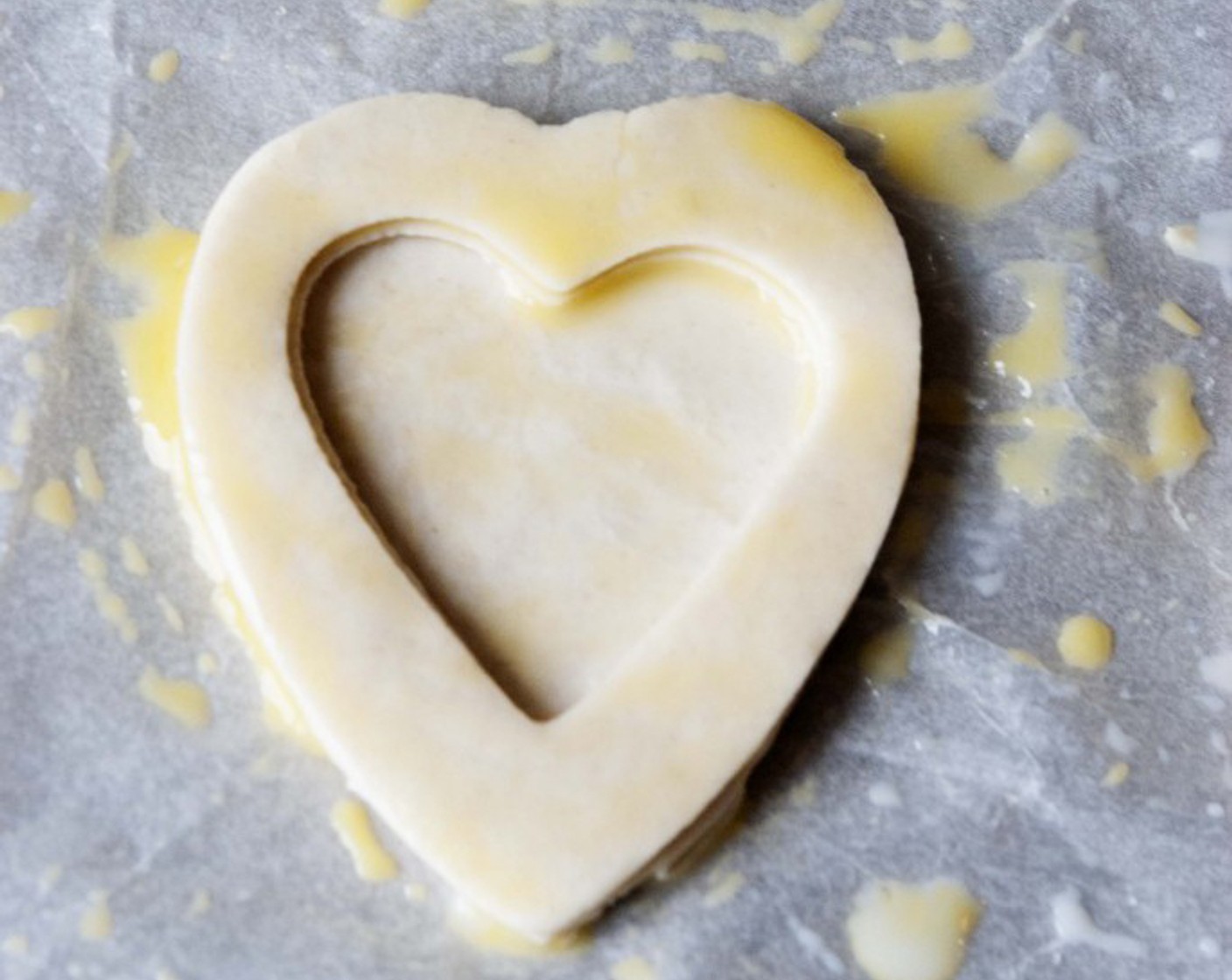 step 14 Now take 3 of the hearts, brush one with the egg-milk wash, then using a smaller cookie cutter, cut off the center of the other 2 hearts, brush them with the wash and place them on top of the first heart.