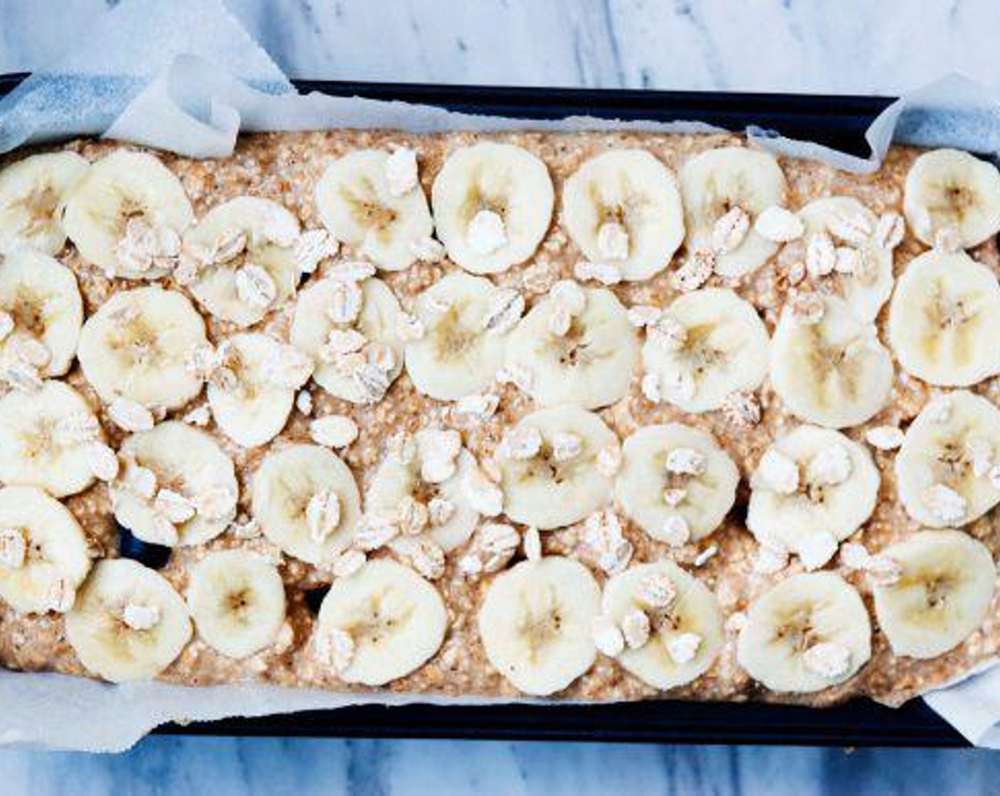 step 5 Transfer the banana bread batter to the prepared baking pan. Smooth into an even layer and top it off with sliced banana and a sprinkle of oats. Bake at 360 degrees F (180 degrees C) for 30-45 min.