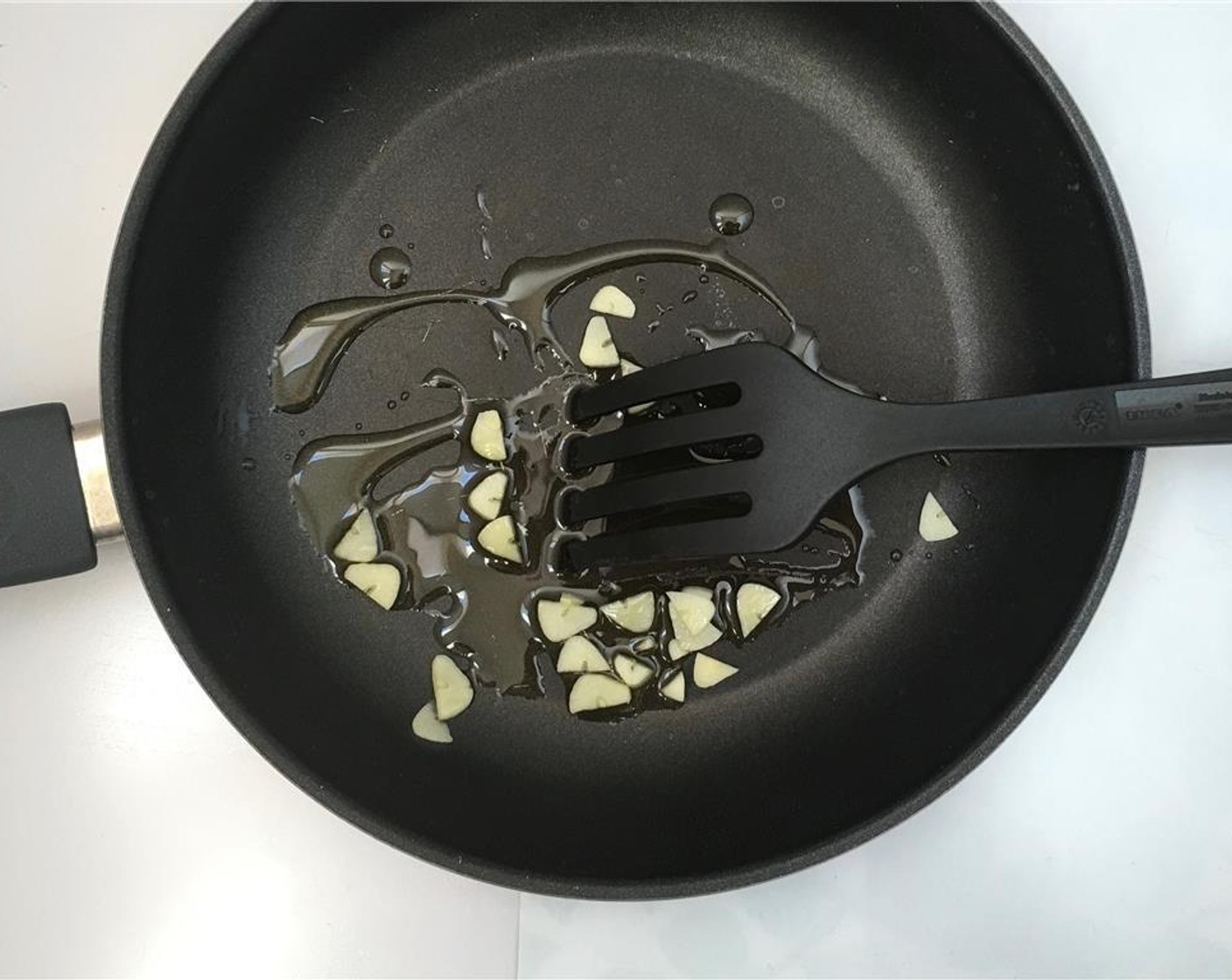 step 1 Peel and slice up the Garlic (1 clove). Add it to a non-stick pan with some good quality Olive Oil (as needed).