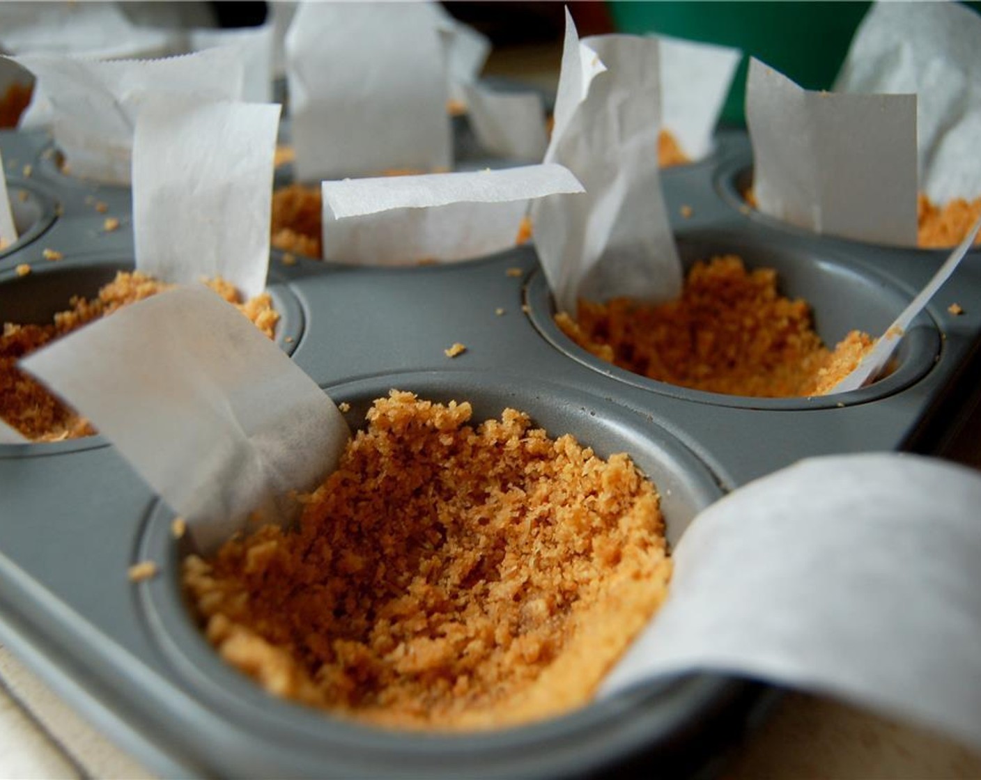 step 3 Press about 2 Tbsp. of the crust mixture into each cup, pressing firmly on the bottom and up the sides of the cup. Place the pan in the freezer until the filling is finished and the crust has set.