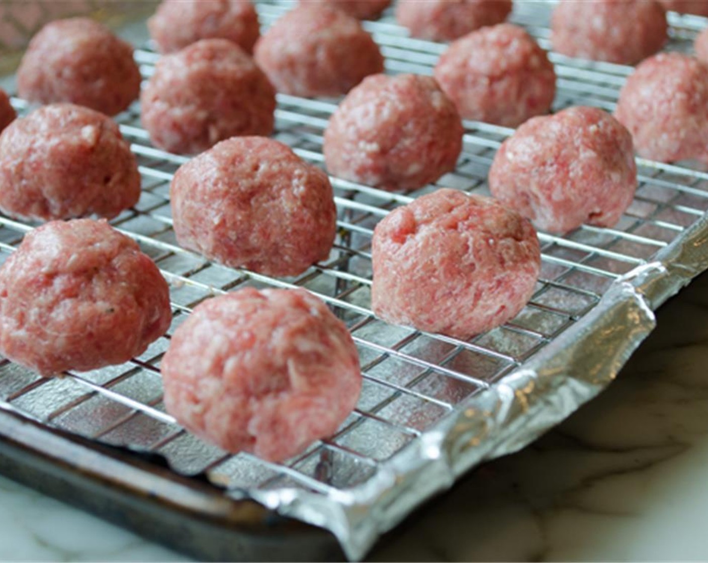 step 7 Using moistened hands (it's sticky and wet hands help; keep wetting them as you go), form the meat mixture into tablespoon-size round meatballs and place on the prepared rack. Bake for about 20 minutes, until just done.