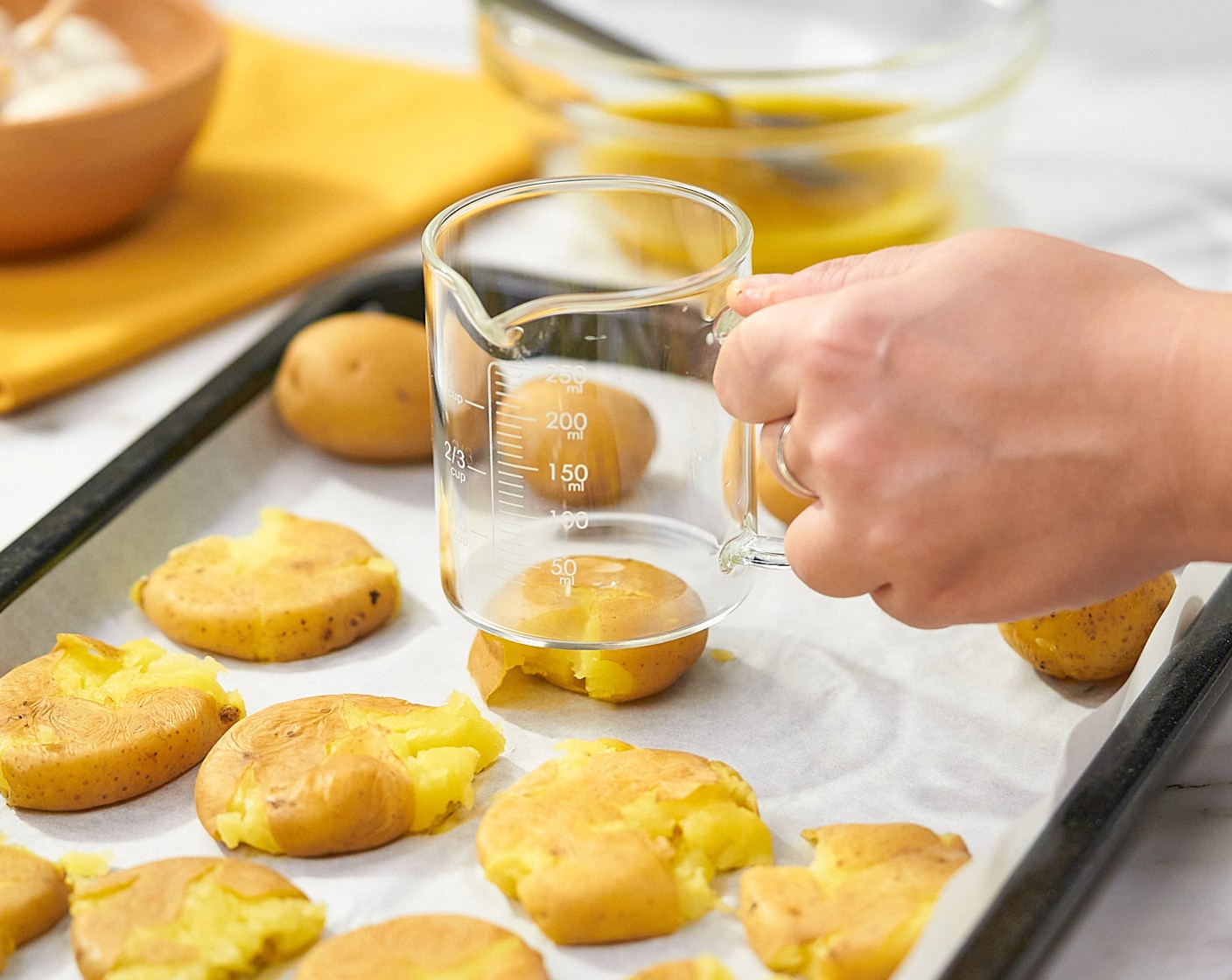 step 5 Add potatoes to the parchment-lined sheet. Using a cup with a flat bottom, gently smash the potatoes, trying to keep them as intact as possible. Use a spatula if needed to help with sticking. Leave some space between them so that they crisp up properly. Use an extra baking sheet if needed.