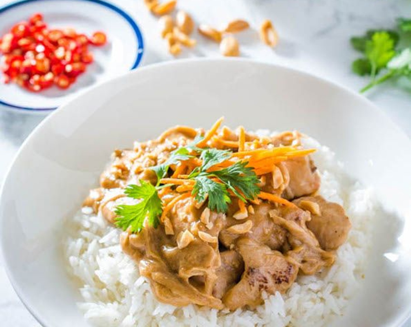 step 8 Serve immediately over steamed rice, with the remaining sauce on the side. Garnish with Dry Roasted Peanuts (1/2 cup), Fresh Cilantro (1/2 cup), and Carrot (1/2 cup).