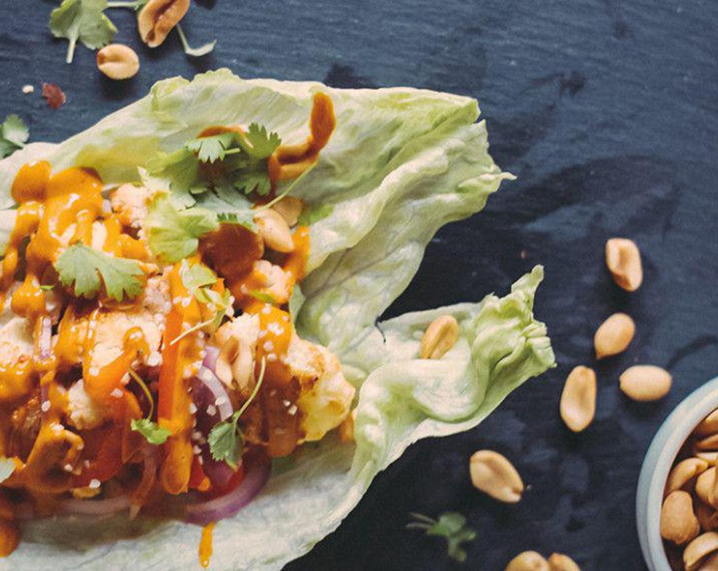 step 5 Allow veggies to cool 3 to 5 minutes, then add cauliflower, red onions, bell pepper, and Peanuts (1/4 cup), to Romaine Lettuce (8). Drizzle with Sriracha sauce, then garnish with Fresh Cilantro (to taste) and Hemp Hearts (to taste).