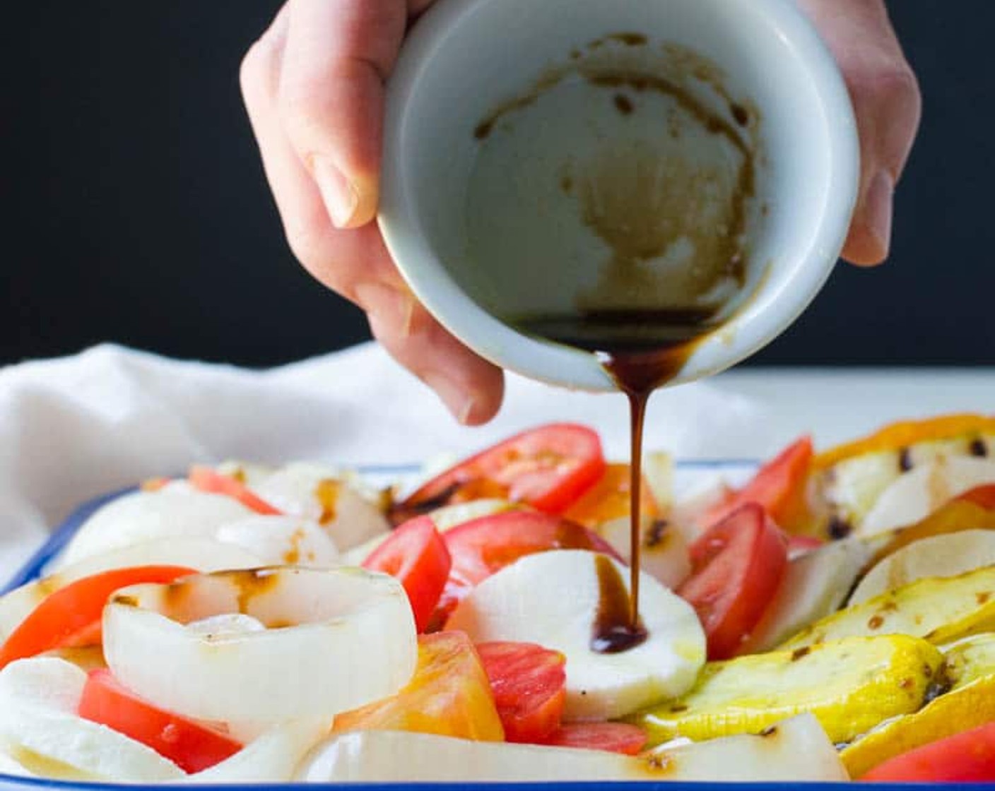 step 7 Use a medium platter with a rim to layer the vegetables, Heirloom Tomato (1), Plum Tomatoes (2), and mozzarella. Drizzle the Aged Balsamic Vinegar (2 Tbsp).