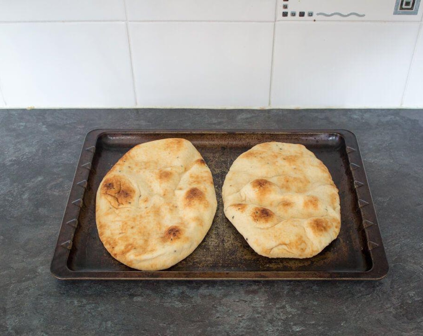 step 2 Take the Naans (2)  out the packet and lay onto a large baking sheet. Sprinkle a little cold water over each one.