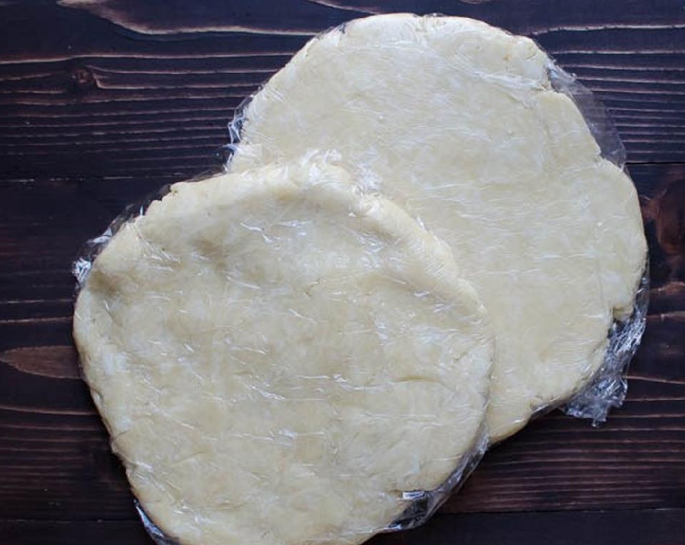 step 3 Transfer the dough into a large bowl and use your hands to form it into a ball. Cut the dough in half, form into two balls and flatten each into a 8" disc. Wrap the discs in plastic wrap and refrigerate for an hour.