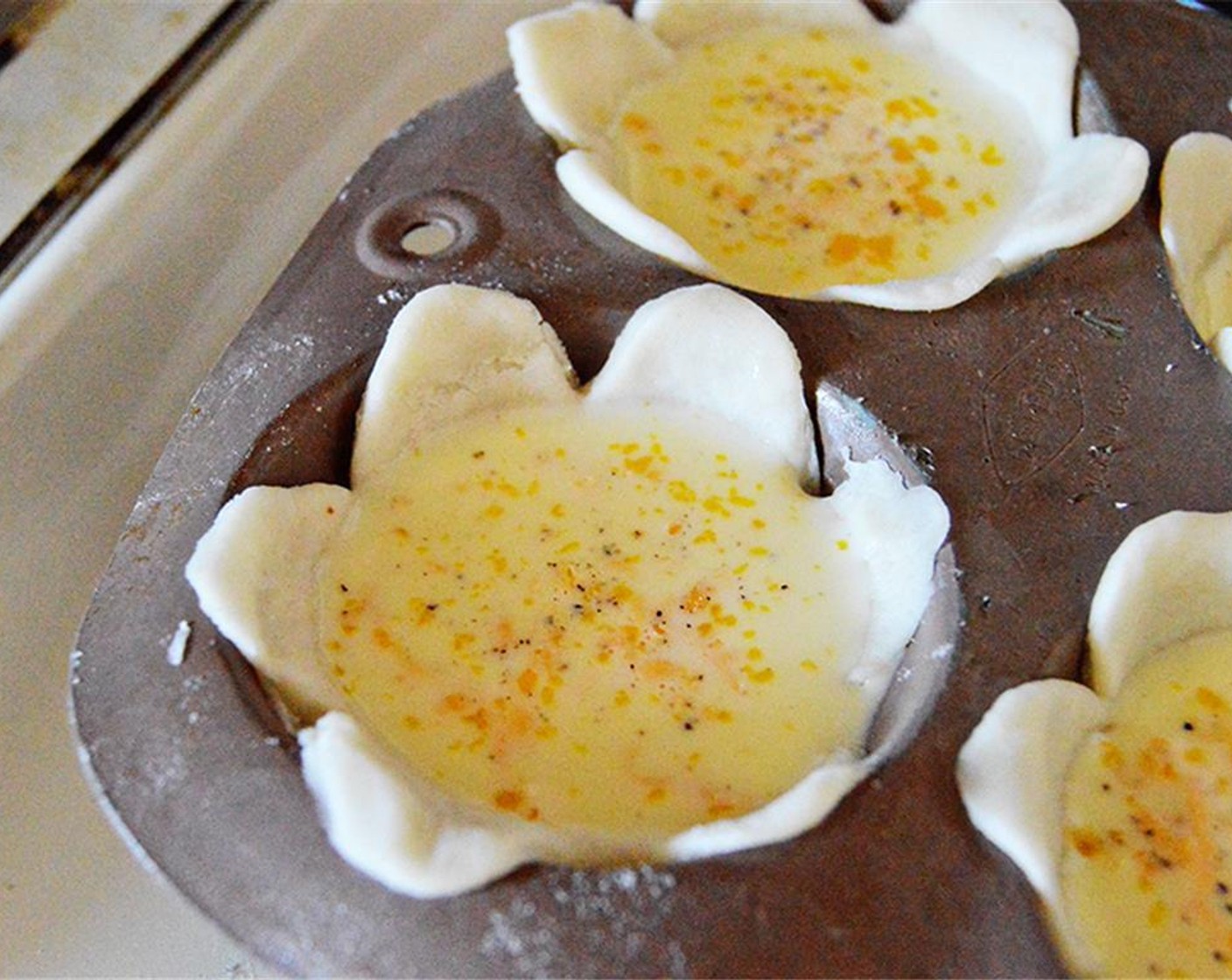 step 4 In another bowl, whisk together Eggs (2), Milk (1 cup), Shredded Cheese (1/4 cup), Salt (to taste), and Ground Black Pepper (to taste). Spoon filling into the flower cups.