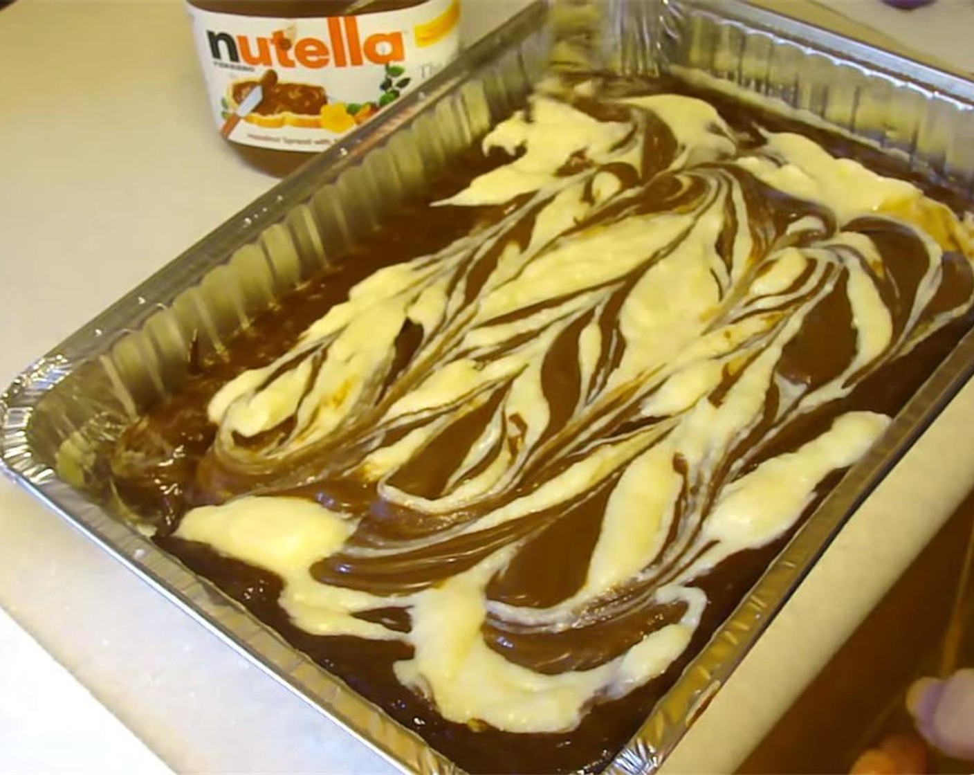 step 5 Pour evenly over the brownie batter. Drop Nutella® (1/3 cup) by the spoonful on top as well, and make swirls in the batter with a knife. Bake for 25-30 minutes. Let cool for at least 10 minutes before cutting into squares.