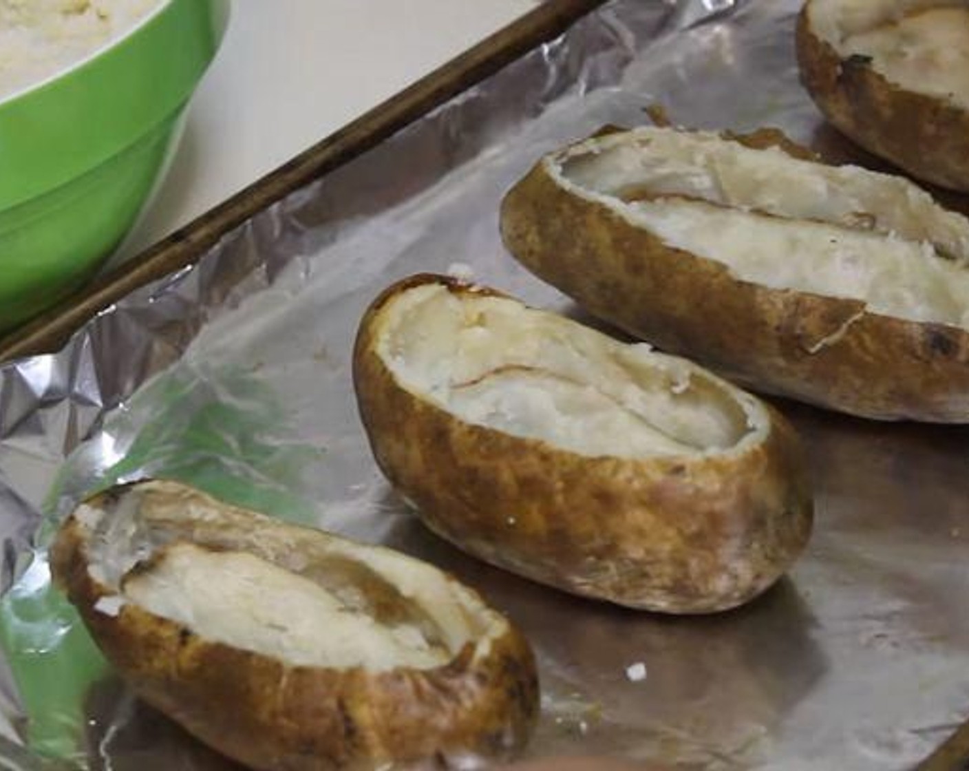 step 2 On the long side of each recently cooked potato, slice off the top. Scoop out and reserve the potato innards, making sure to leave a bit of a wall to give the potato structure.