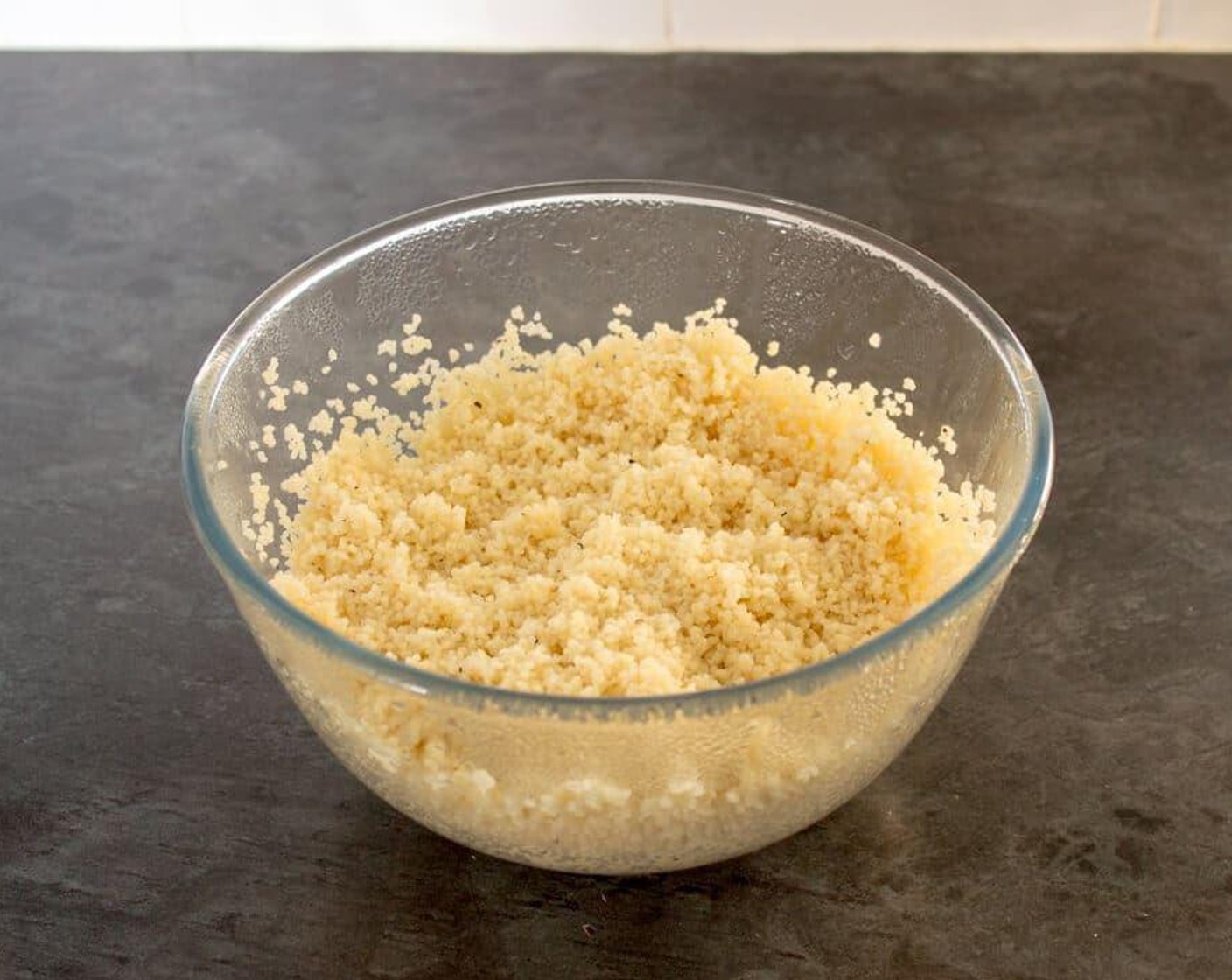 step 1 In a large glass bowl, add the Couscous (3/4 cup), a generous helping of Salt (to taste) and Ground Black Pepper (to taste), and about 1 tablespoon of the oil from the sundried tomatoes jar. Pour in the Water (1 1/4 cups) stir with a fork and cover with cling film. Leave to one side whilst we prepare the rest of the dish.