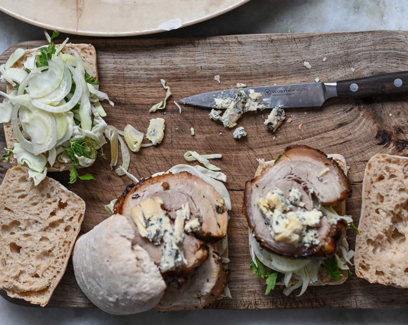 step 12 To assemble a porchetta sandwich, halve Ciabatta Bread (as needed) and top with some slaw followed by a slice or two of porchetta. Crumble a little Blue Cheese (as needed) over the top and close the roll. Serve with a few glasses of wine if desired.