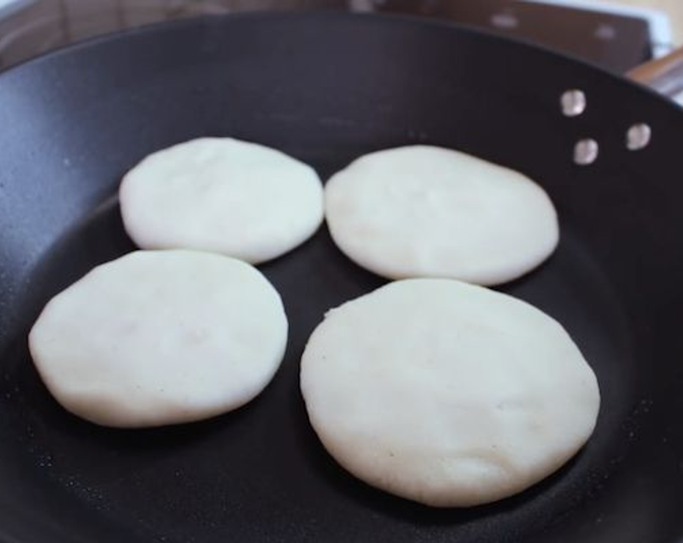step 4 In a large pan over medium heat, add a little bit of oil and spread using a napkin. Place the arepa down and cook for 5-7 minutes without moving them.