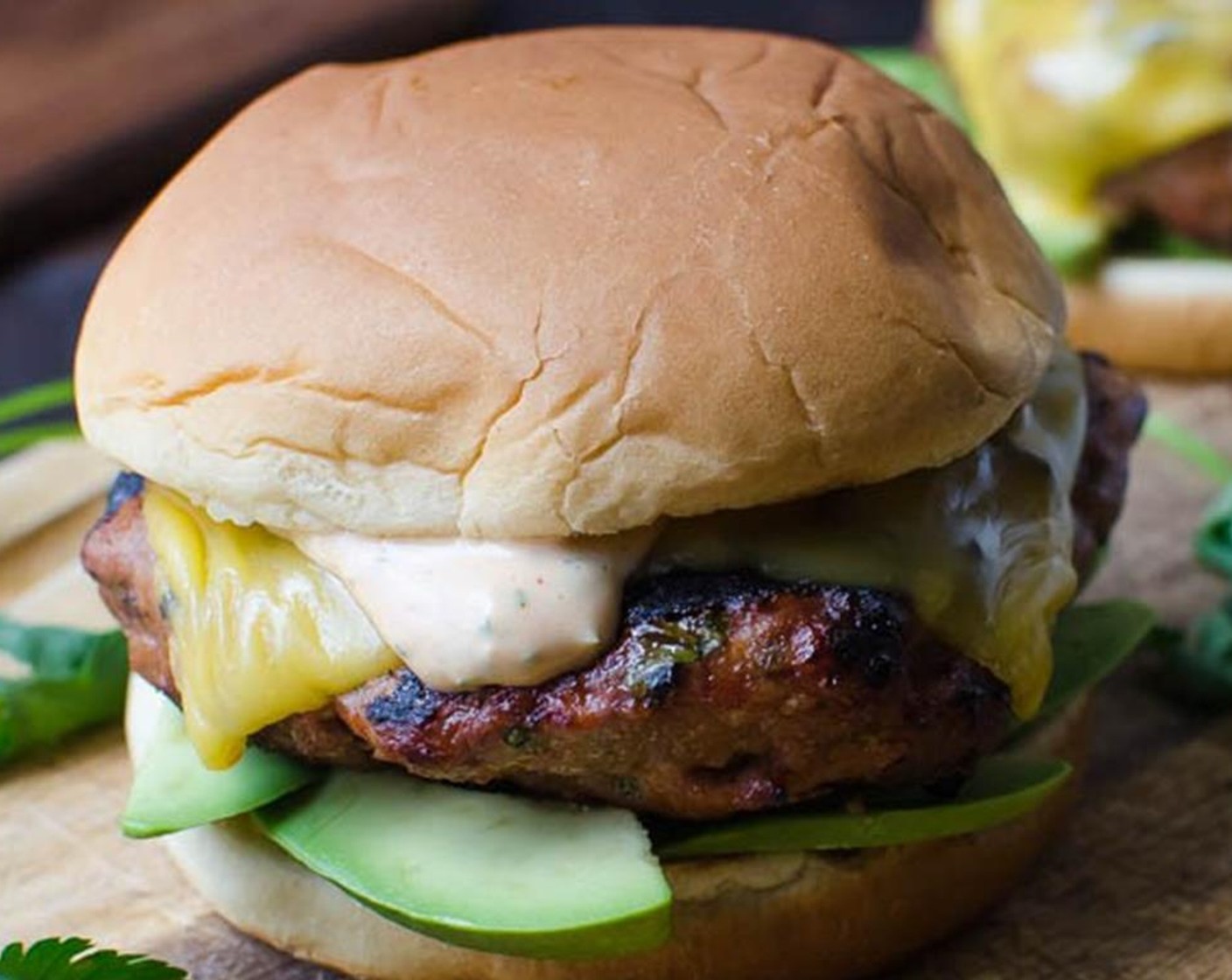 step 8 Assemble the burgers with sliced Avocado (1) on the bottom Hamburger Buns (5), followed by the burger, a tablespoon of sriracha aioli and extra cilantro leaves if desired.