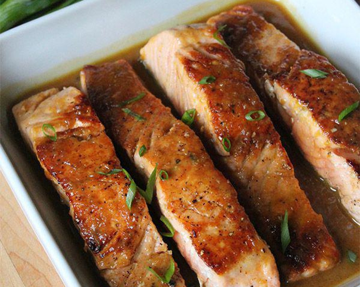step 6 Transfer to a rimmed plate or serving dish. Pour the glaze over the salmon, making sure to coat the fillets. Sprinkle with the Scallions (to taste) if using and serve hot.