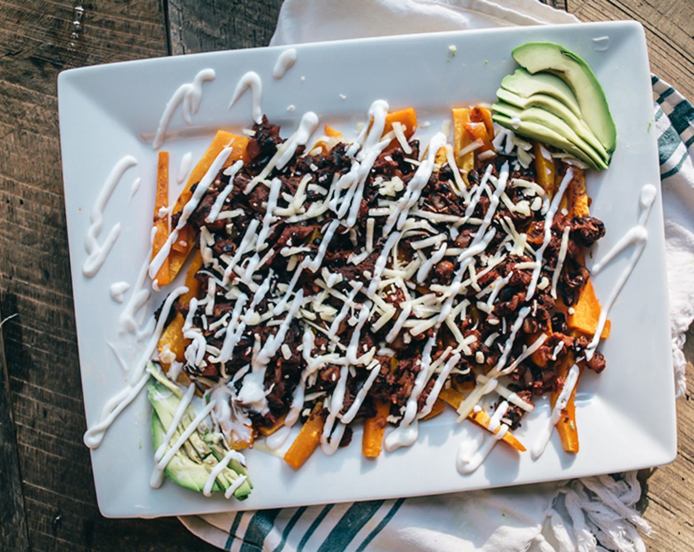 step 6 Once fries are cooked and have cooled for a minute, layer them on large platter or two separate plates and top with black bean vegetarian chili mixture.  Sprinkle with Shredded Cheddar Cheese (1/4 cup), drizzle with Sour Cream (2 Tbsp)) and garnish with sliced Avocado (1/2).